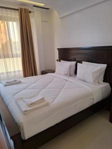 a large bed with white sheets and white pillows at The Sailors Address in Thika