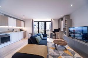 a living room with a blue couch and a tv at Spacious & Smart Studio Flat with Balcony - Zone1 in London