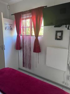 a bedroom with red curtains and a window at Bougain Villa Self-catering ,Darling in Darling