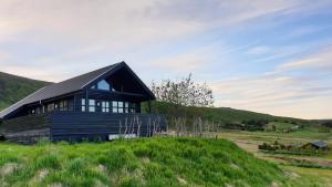a black house on a hill with a green field at Geysir Cabins - Golden Circle Cabin only 800m from Geysir in Selfoss