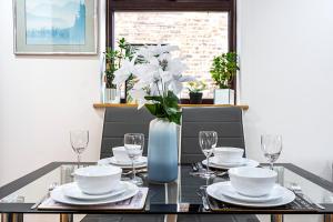 2 Bedroom Apartment by AV Stays Short Lets Southwark London With Free WiFi في لندن: طاولة طعام مع صحون و كاسات و مزهرية