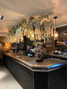 un bar con flores colgando del techo en The White Hart Hotel, en Uttoxeter