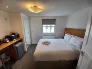 Habitación de hotel con cama y microondas en B&B Belgravia, en Londres