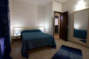 a bedroom with a bed with a green bedspread and a mirror at Residence Mareluna in Castellammare del Golfo