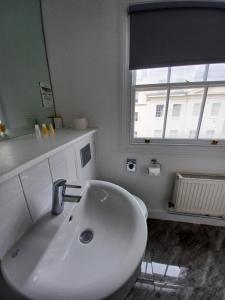baño con lavabo blanco y ventana en B&B Belgravia, en Londres