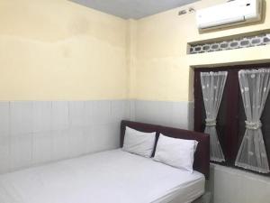 een slaapkamer met een bed met witte lakens en een raam bij OYO 93864 Wisma Gading Syariah in Pemalang