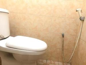 een badkamer met een toilet en een slang aan de muur bij OYO 93864 Wisma Gading Syariah in Pemalang