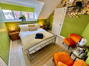 um quarto com paredes verdes e uma cama com cadeiras laranja em Lemur Lodge - Boutique Apartments - Short Stroll to The Beach em Bournemouth