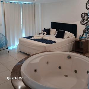 een wit bad in een kamer met een bed bij Pousada Mediterrânea in Pipa