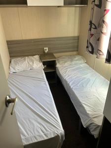 two beds in a small room with a desk at Lido Beach Caravan in Prestatyn
