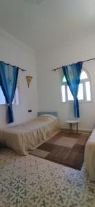 a bedroom with a bed with blue curtains and a window at Villa chez NADA in Essaouira