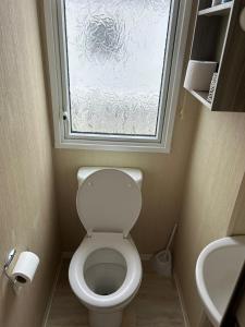 a small bathroom with a toilet and a window at Lido Beach Caravan in Prestatyn +6 photos