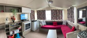 a living room with a couch and a tv at Lido Beach Caravan in Prestatyn