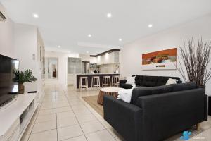 sala de estar con 2 sofás negros y cocina en Batemans Bay Apartment, en Batemans Bay