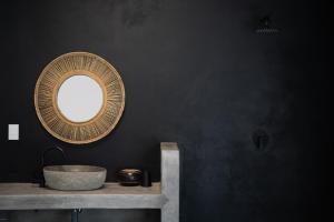 a bathroom with a round mirror on a black wall at Ivory House in Marloth Park