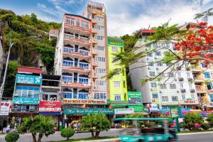 a city street with tall buildings and a blue bus at Star Hotel in Cat Ba