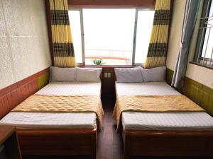 two beds in a room with two windows at Star Hotel in Cat Ba