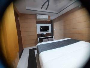 a small bedroom with a bed and a tv at Hotel Asha Delight in Rishīkesh