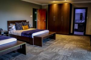 a bedroom with two beds and a wooden cabinet at La Joya Lodge Conference Centre and Spa in Pelindaba