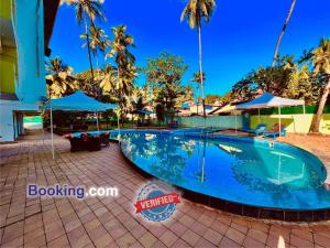 a swimming pool at a resort with palm trees at Shivam Resort With Swimming Pool ,Managed By The Four Season - 1 km from Calangute Beach in Goa