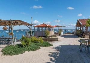 a beach with tables and umbrellas and the ocean at La Cabane de Didi in Andernos-les-Bains
