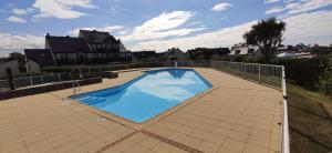 una gran piscina en un patio de azulejos en Maison 4 a 6 personnes proche Océan, piscine partagée, en Clohars-Carnoët