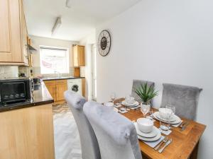 2 Bed House by AV Stays Short Lets Merseyside في سانت هيلينز: مطبخ مع طاولة خشبية مع كراسي حوله