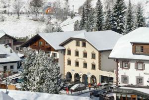 a building with snow on the roofs of a town at Cësa Panaval Apartments in Santa Cristina Gherdëina