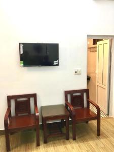 2 sillas, mesa y TV en la pared en Sofia Tống Duy Tân, en Sầm Sơn