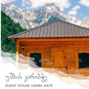a small wooden house with mountains in the background at Guest House Ushba Gate in Mestia