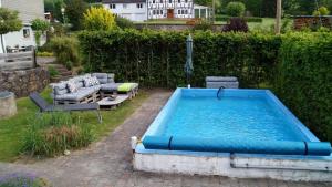 una piscina en un patio con sillas y sombrilla en Ferienwohnung Kebben en Kirchhundem