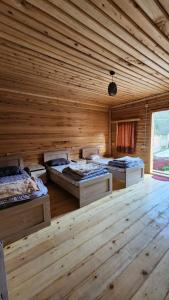 a room with three beds in a wooden room at Guest House Ushba Gate in Mestia