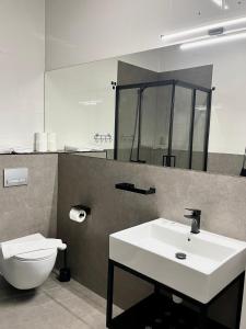 a bathroom with a white sink and a toilet at Apartamenty na Spokojnej in Kołobrzeg