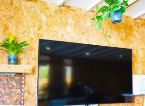 a flat screen tv sitting on a wall with potted plants at Zen Garden Cottage - Patio & Parking by the Bay in Poole