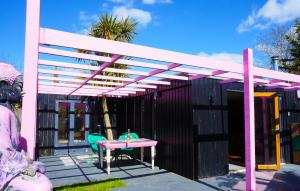 a pink pergola on a patio with a table and chairs at Zen Garden Cottage - Patio & Parking by the Bay in Poole