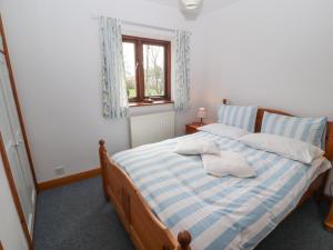 a bedroom with a blue and white bed with a window at Barn Cottage in Carnforth