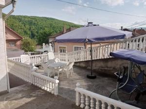 a balcony with white chairs and an umbrella at Apartmani Stojković Kuršumlija in Kuršumlija