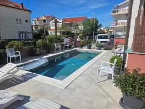 a swimming pool in the middle of a patio with chairs at Apartmani Paula in Vodice