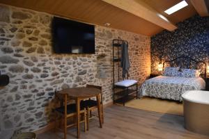 a bedroom with a stone wall with a bed and a table at Cabana de Pili in A Estrada
