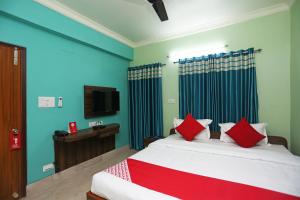 um quarto com uma cama com almofadas vermelhas e uma televisão em OYO Executive Guest House em Pānchuria