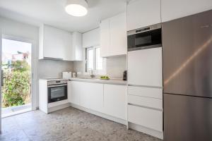 a kitchen with white cabinets and a stainless steel refrigerator at Serenity Seafront garden villa in Pefkohori
