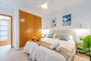 - une chambre avec un grand lit blanc et une armoire en bois dans l'établissement CARIHUELA - Beach & Sun, à Torremolinos