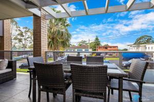 patio con mesa y sillas en el balcón en Batemans Bay Apartment, en Batemans Bay