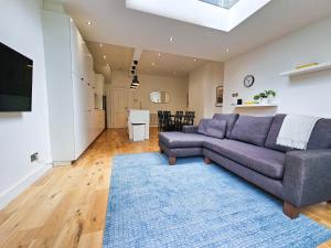 uma sala de estar com um sofá e um tapete azul em Fresh & Modern House with Games Room & Garden em Londres
