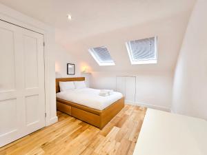 um quarto com uma cama e duas janelas em Fresh & Modern House with Games Room & Garden em Londres