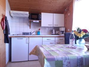 uma cozinha com armários brancos e uma mesa com um vaso de flores em Ferienhaus Spatz 1 