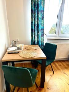 a dining room table with two green chairs and a window at Skalny Widok in Hucisko