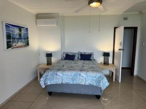 a bedroom with a bed with blue pillows and two tables at Ocean Vista in Amanzimtoti