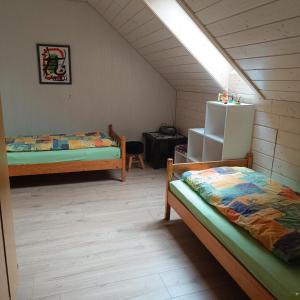 Cette chambre mansardée comprend deux lits et un réfrigérateur. dans l'établissement Burgenwelt im wilden Süden, à Münsingen