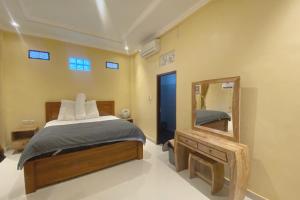 een slaapkamer met een bed en een spiegel bij Capital O 93844 Arta Adi Homestay in Bangli